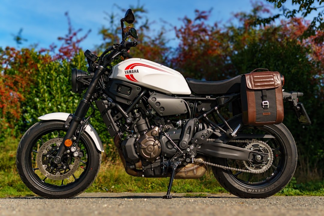 White yamaha motorcycle with brown saddlebag parked outdoors.