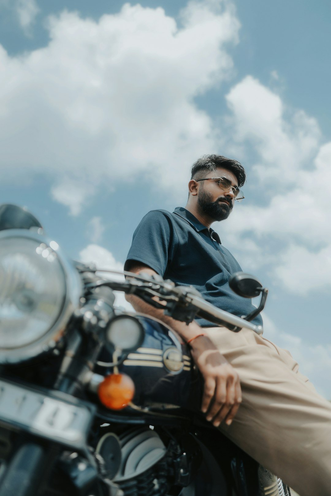 Man sitting on a motorcycle under a cloudy sky.