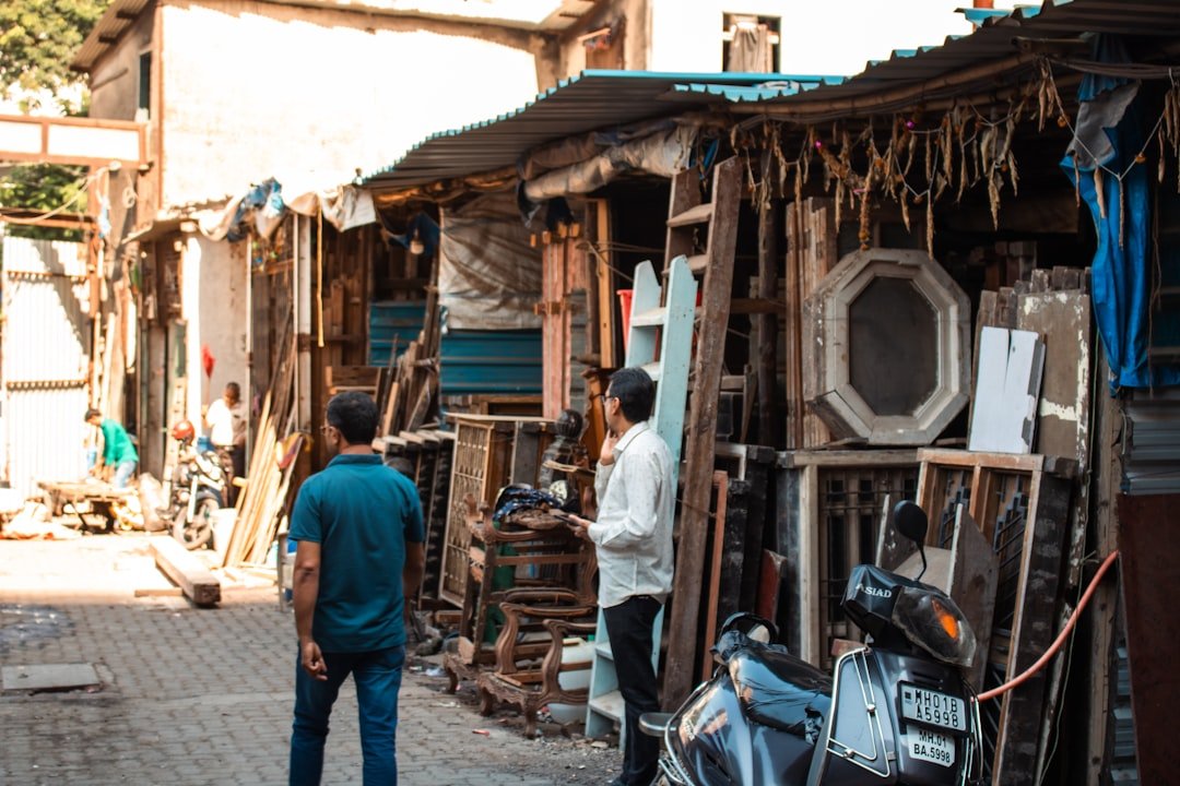Two men stand near a cluttered market stall.