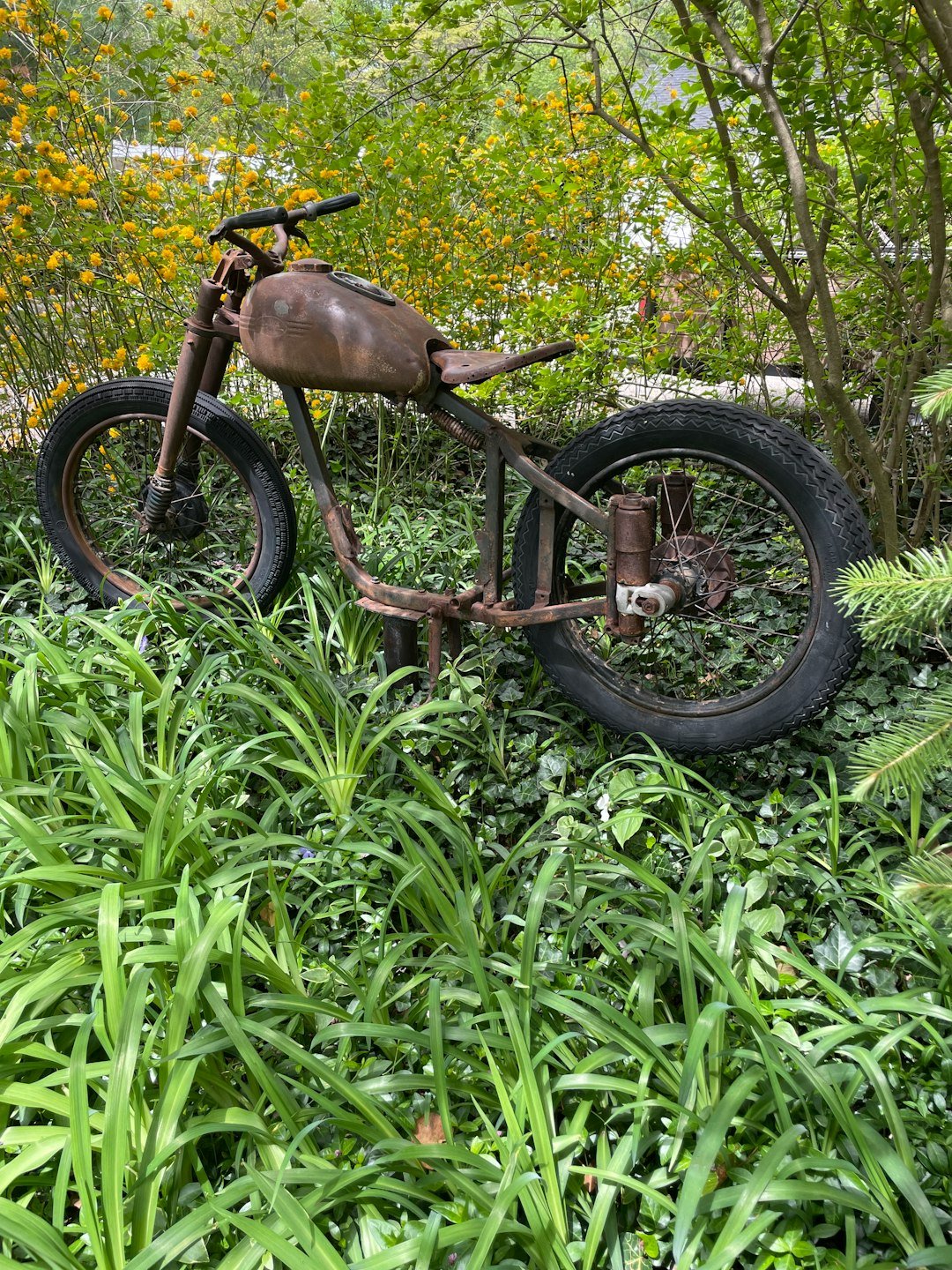 an old motorcycle sitting in the middle of a lush green field