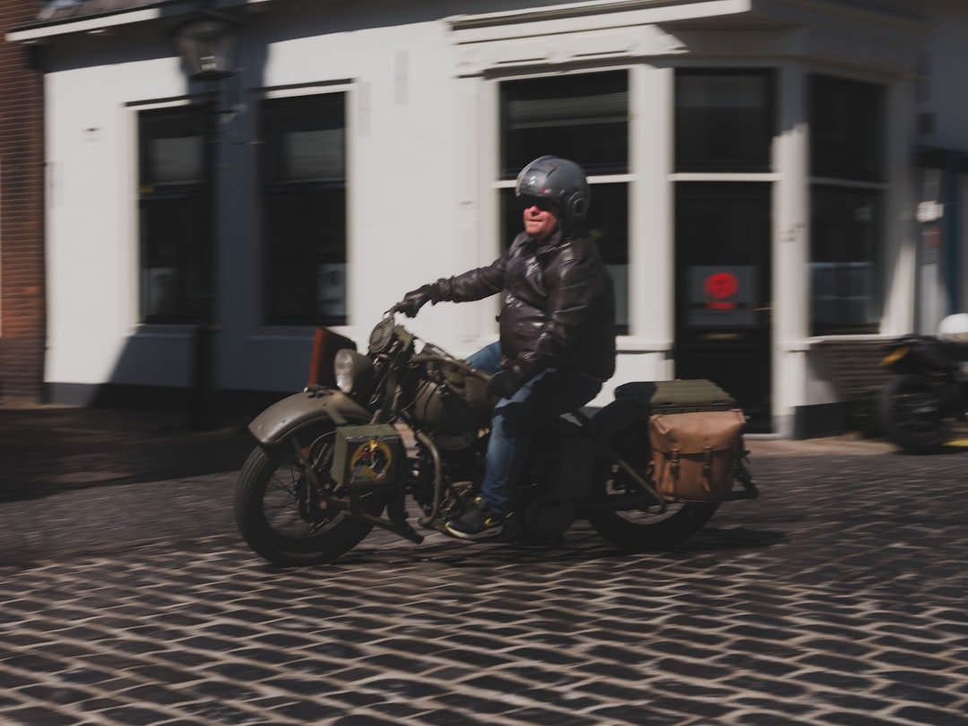A person rides a vintage motorcycle down the street.