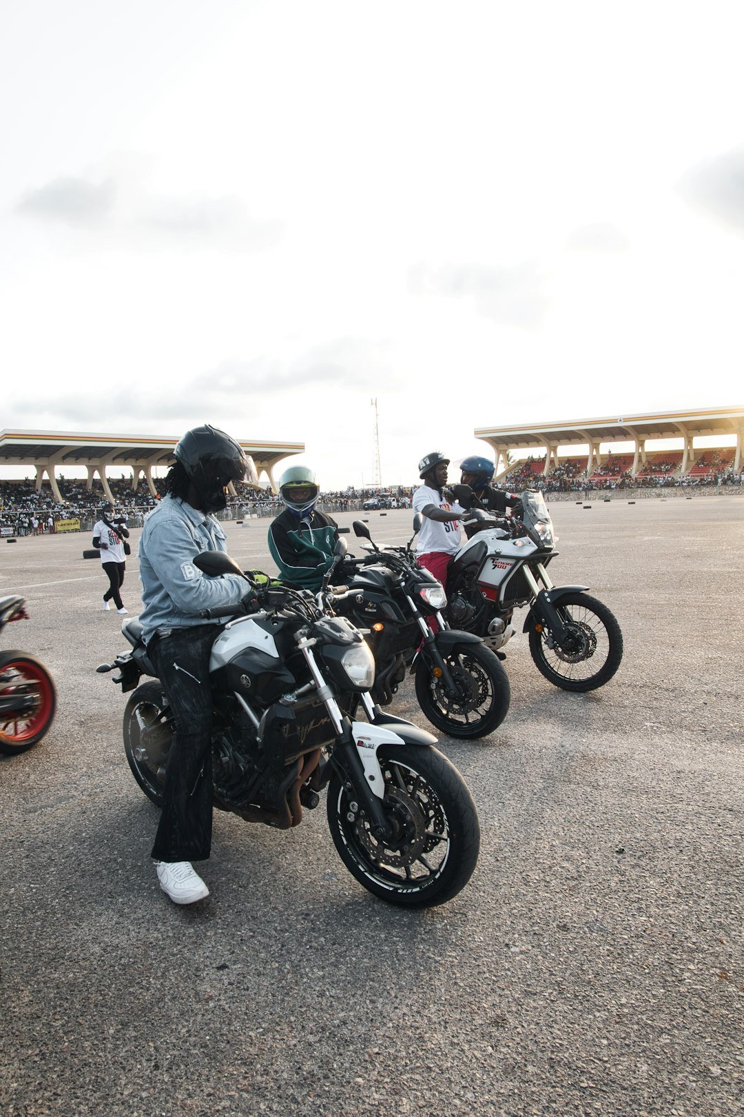 Four people on motorcycles at an outdoor event