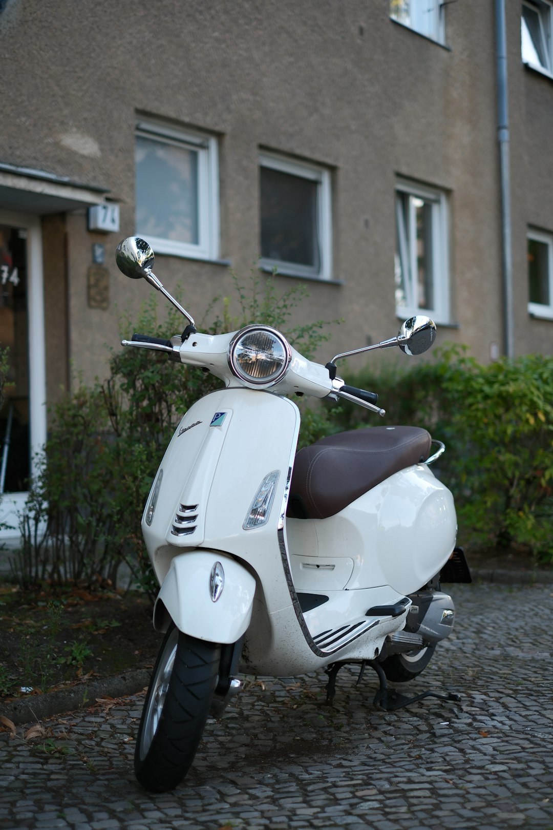 A white scooter parked in front of a building