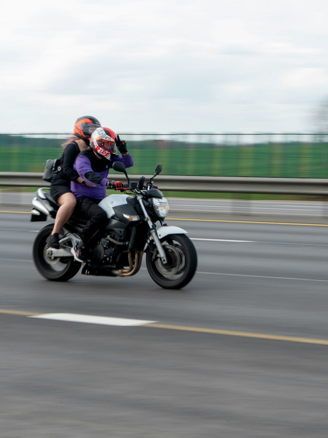 Two people ride a motorcycle on a highway.