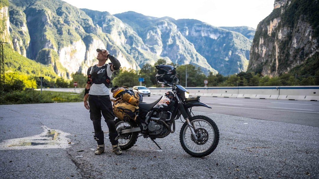 Motorcyclist with loaded bike in mountainous landscape