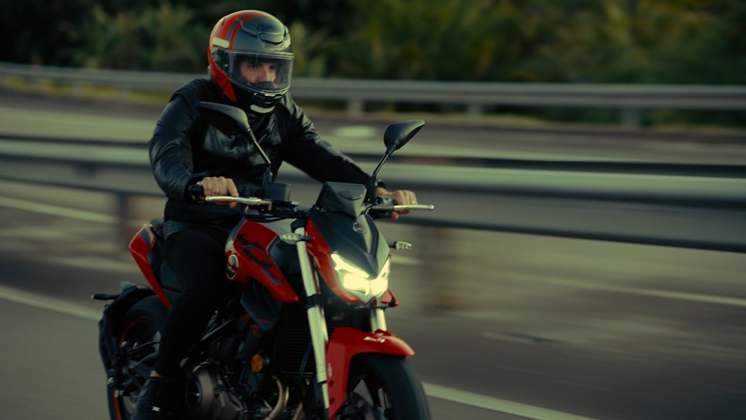Man riding a red motorcycle on a road.