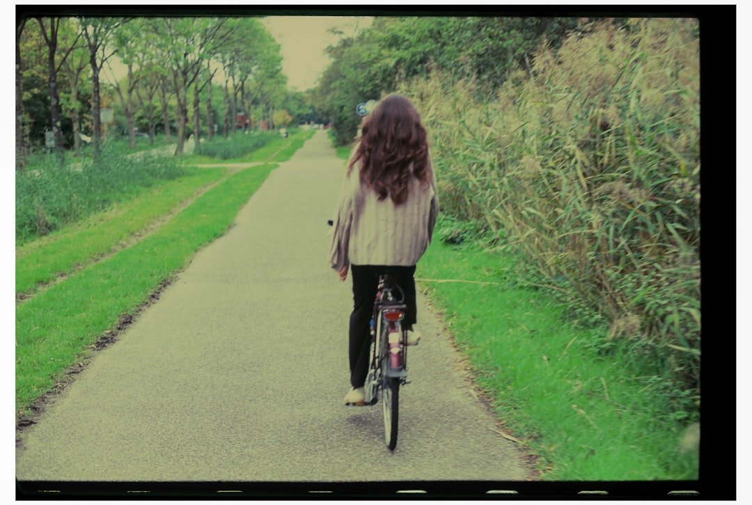 Woman riding bicycle on a path next to reeds.