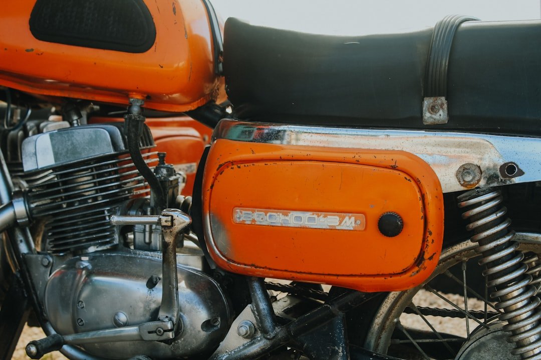 a close up of an orange motorcycle with a black seat