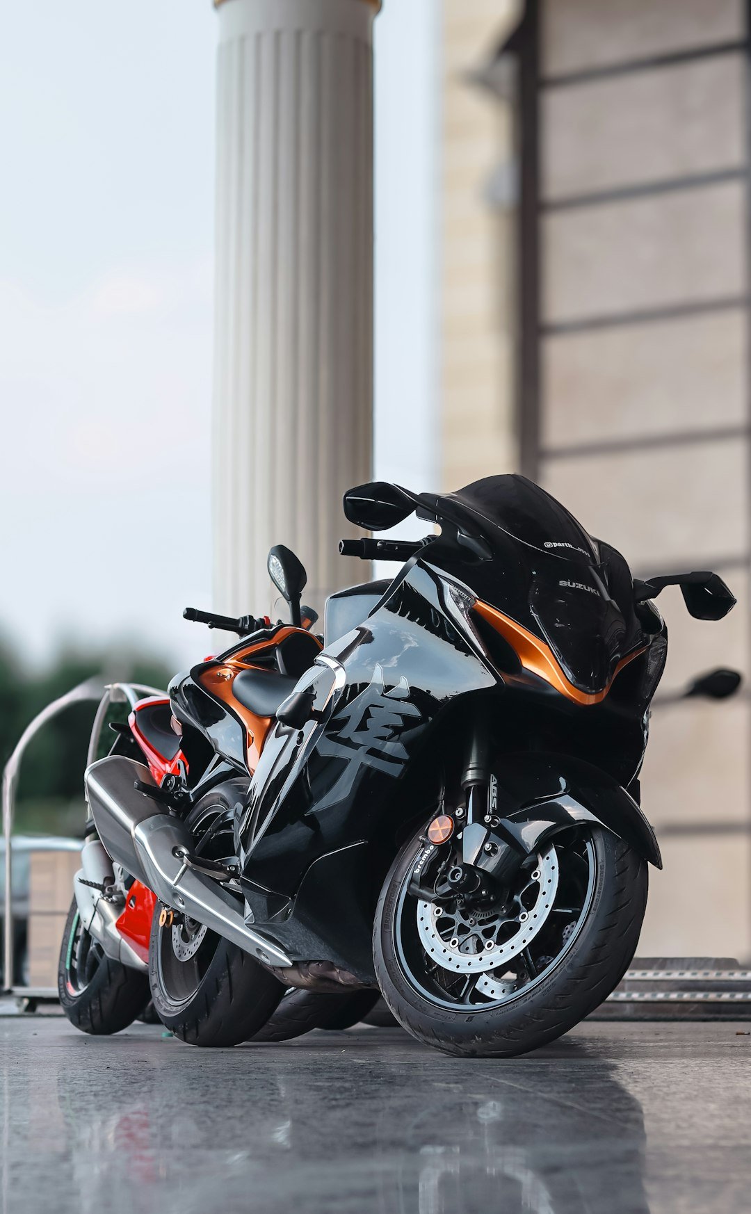 Two sleek black and orange motorcycles parked outside.