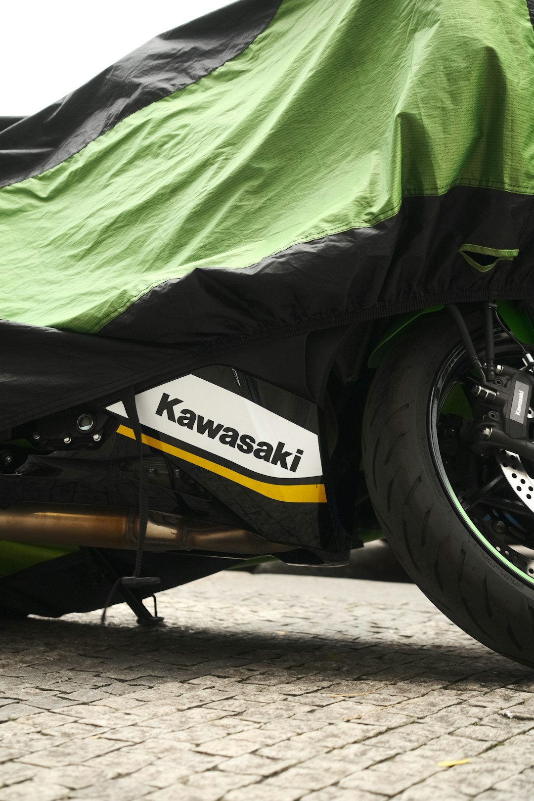 Motorcycle covered with green and black tarp