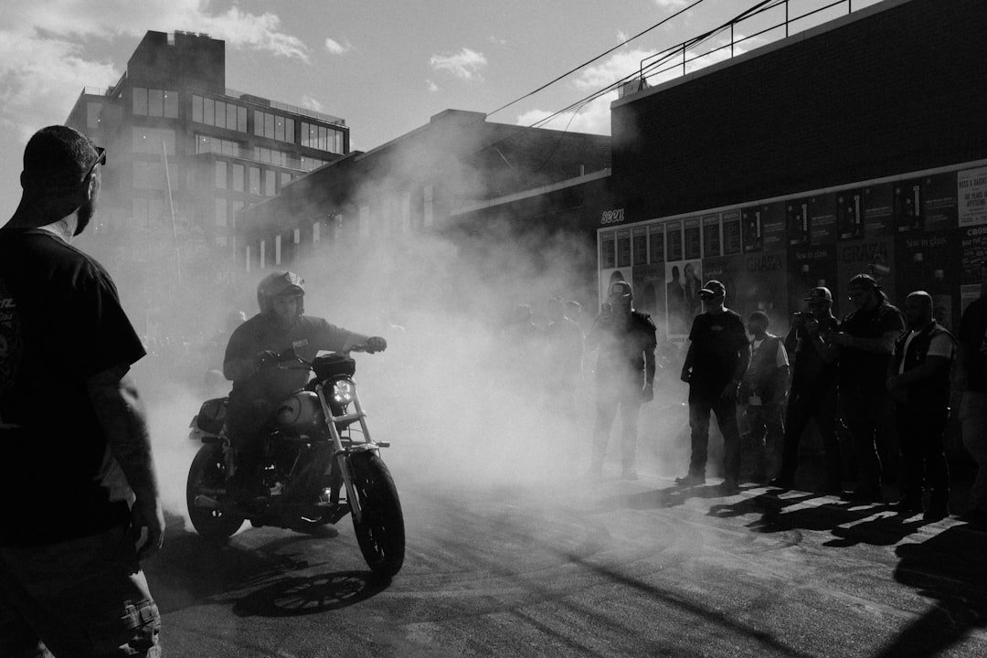 Motorcyclist performs burnout in smoky street with onlookers