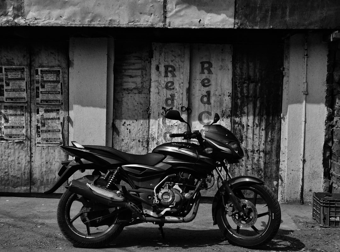 A black motorcycle parked in front of a weathered doorway.