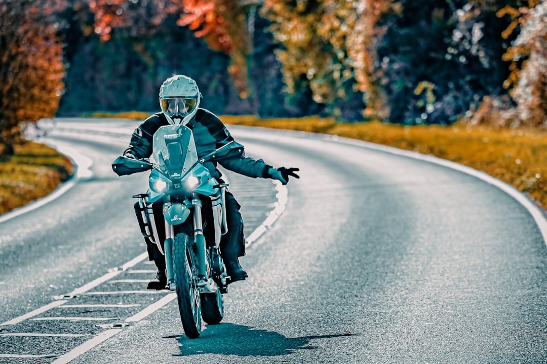 Motorcyclist riding on a winding road in autumn.