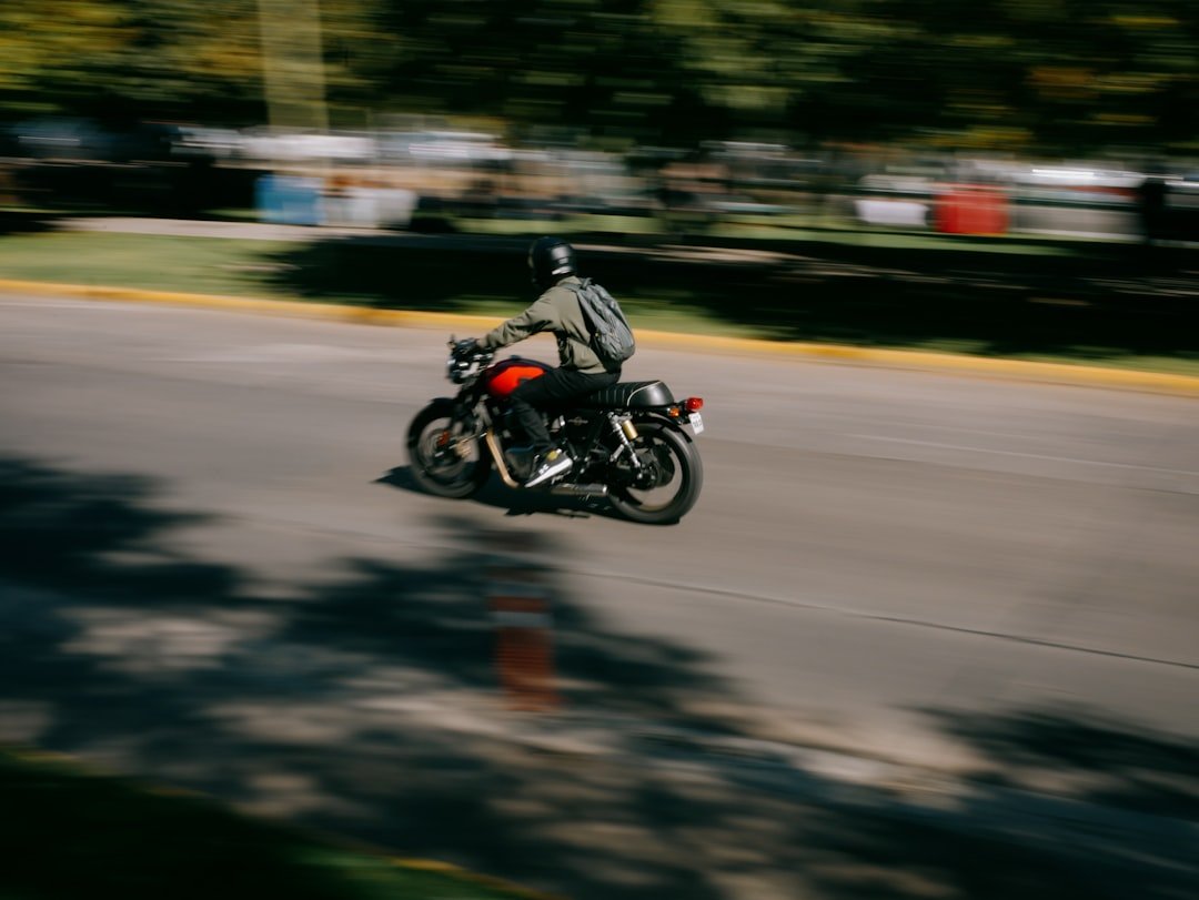 Motorcyclist rides down a blurred road with trees