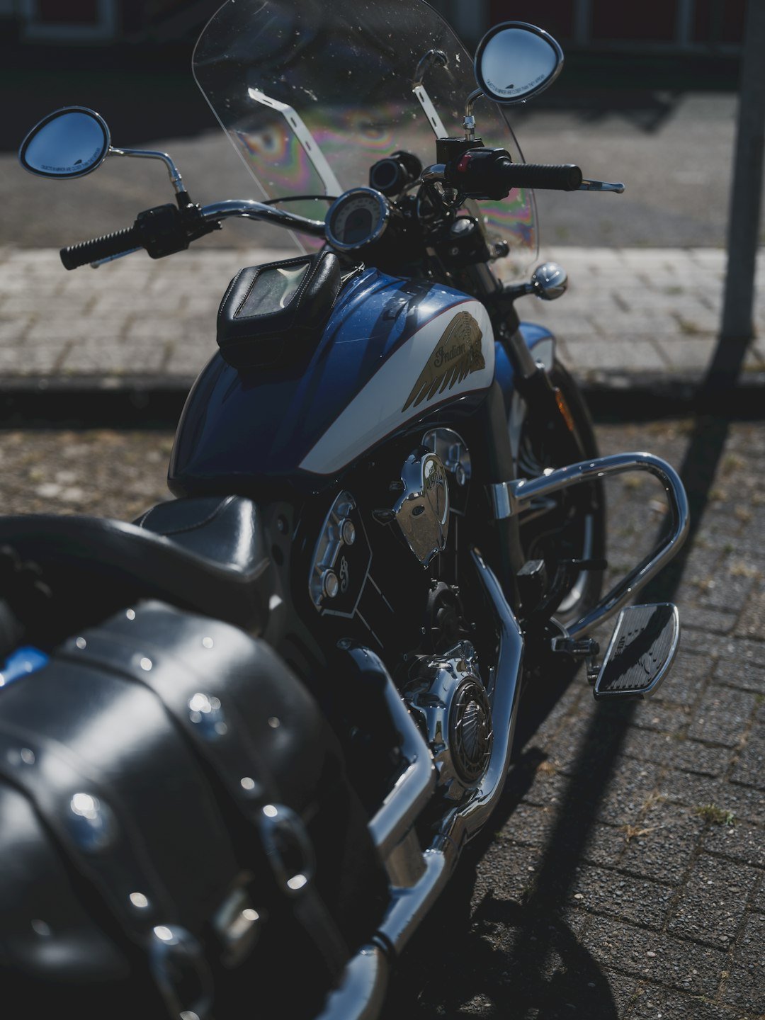 A blue and white motorcycle is parked in the sun.
