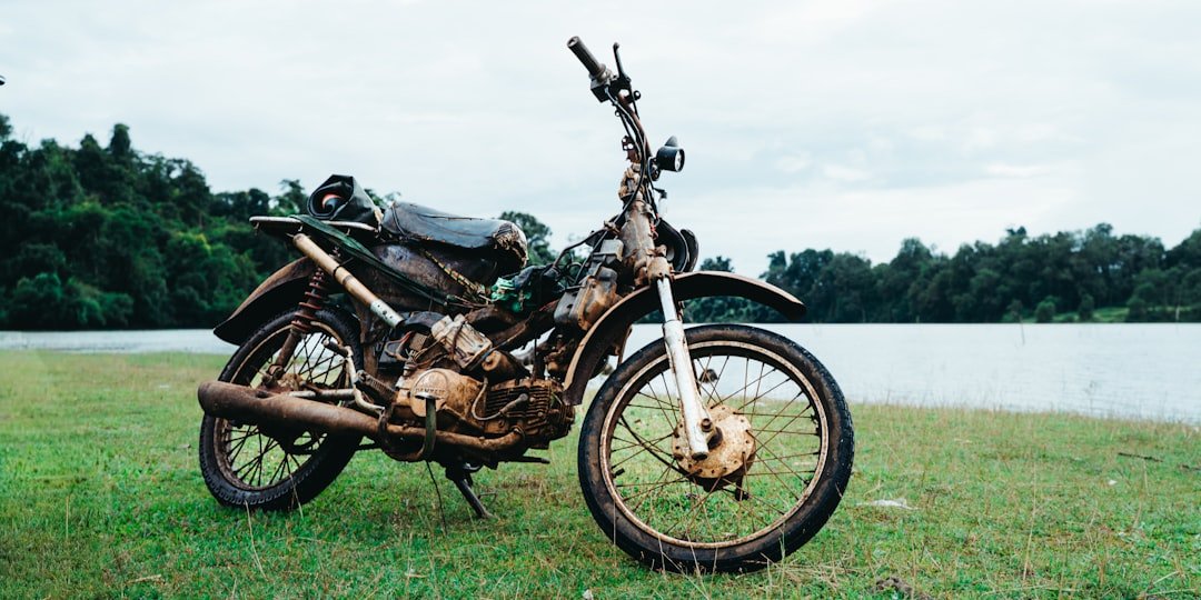 Old motorcycle parked on grassy field near water