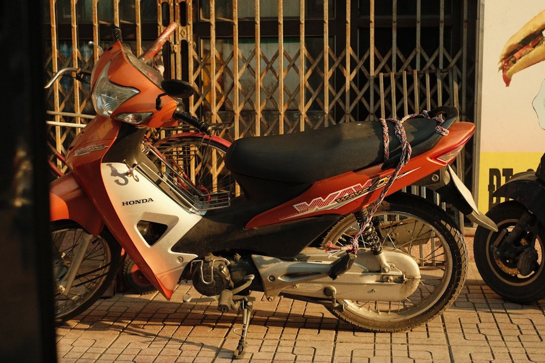 a red and white motorcycle parked in front of a gate