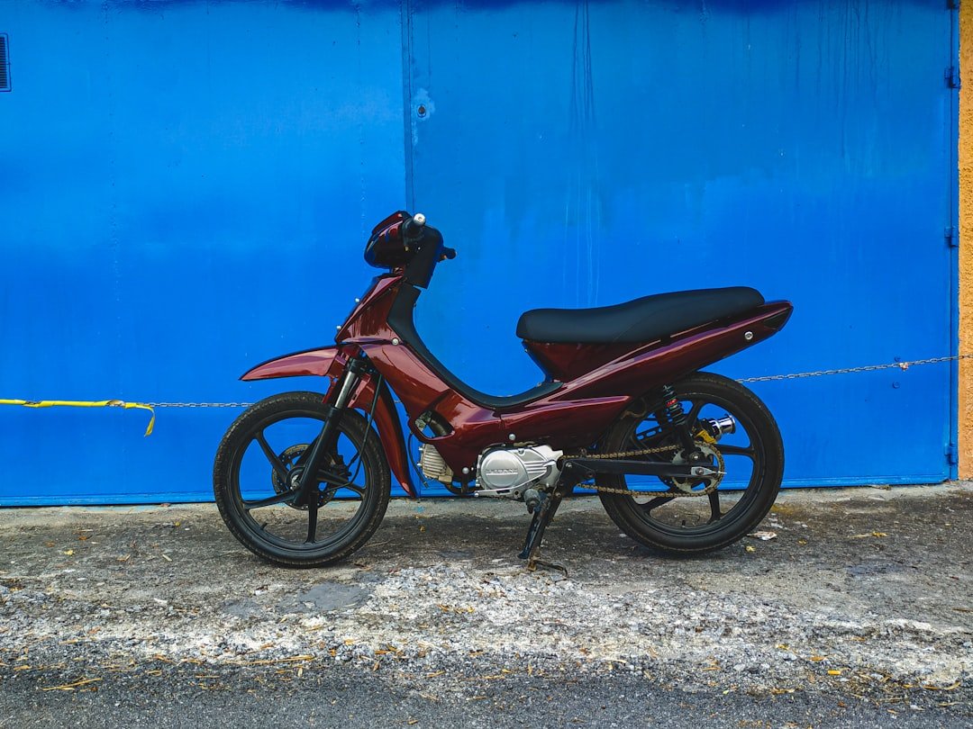 red motorcycle parked beside blue painted wall