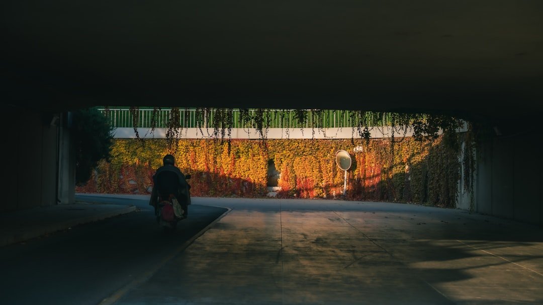 Person on scooter rides through colorful underpass mural.