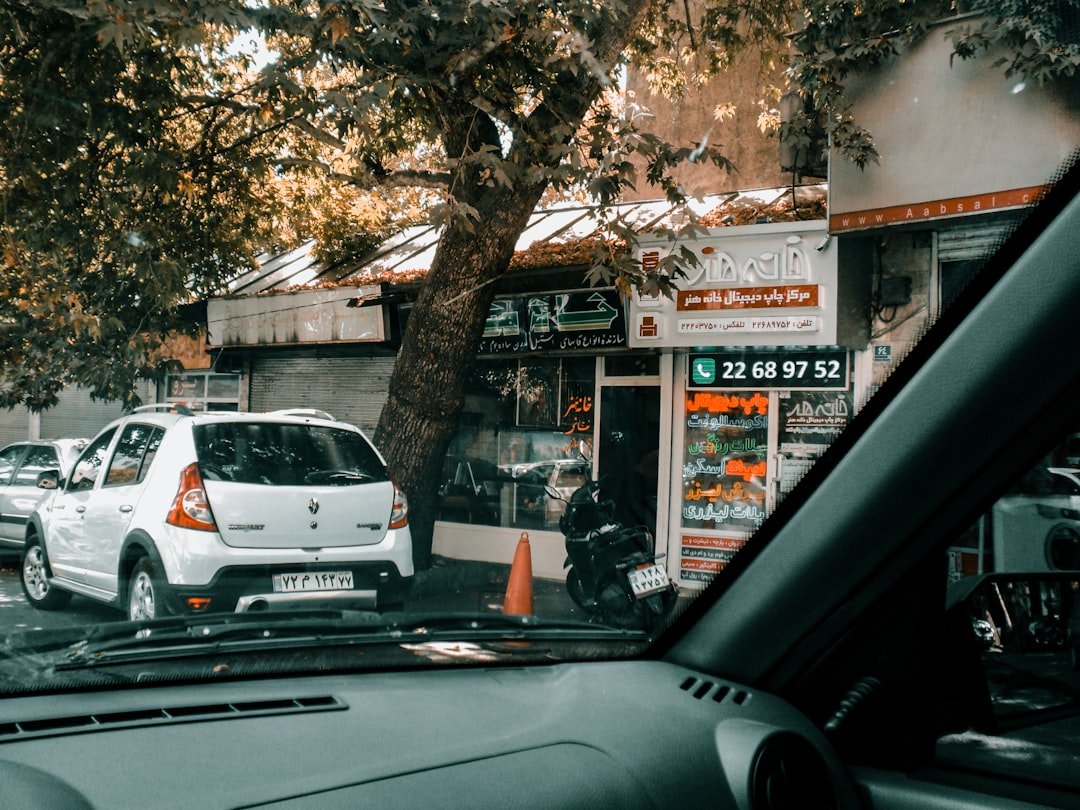White car parked on street near shops.
