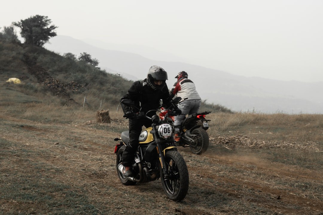 two people riding motorcycles on a dirt road