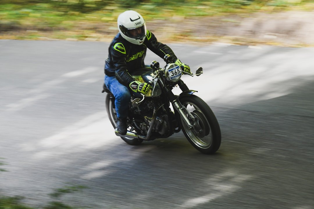 Motorcyclist riding a vintage bike on a road.
