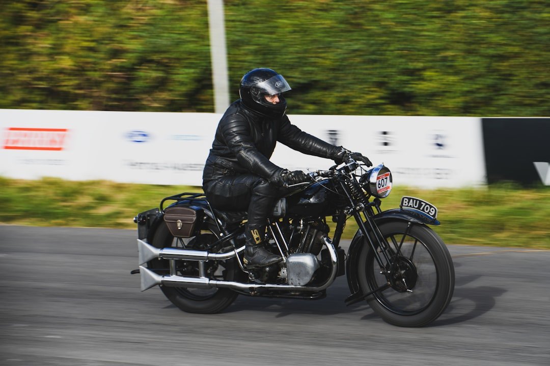 Rider in black leather on vintage motorcycle races past.