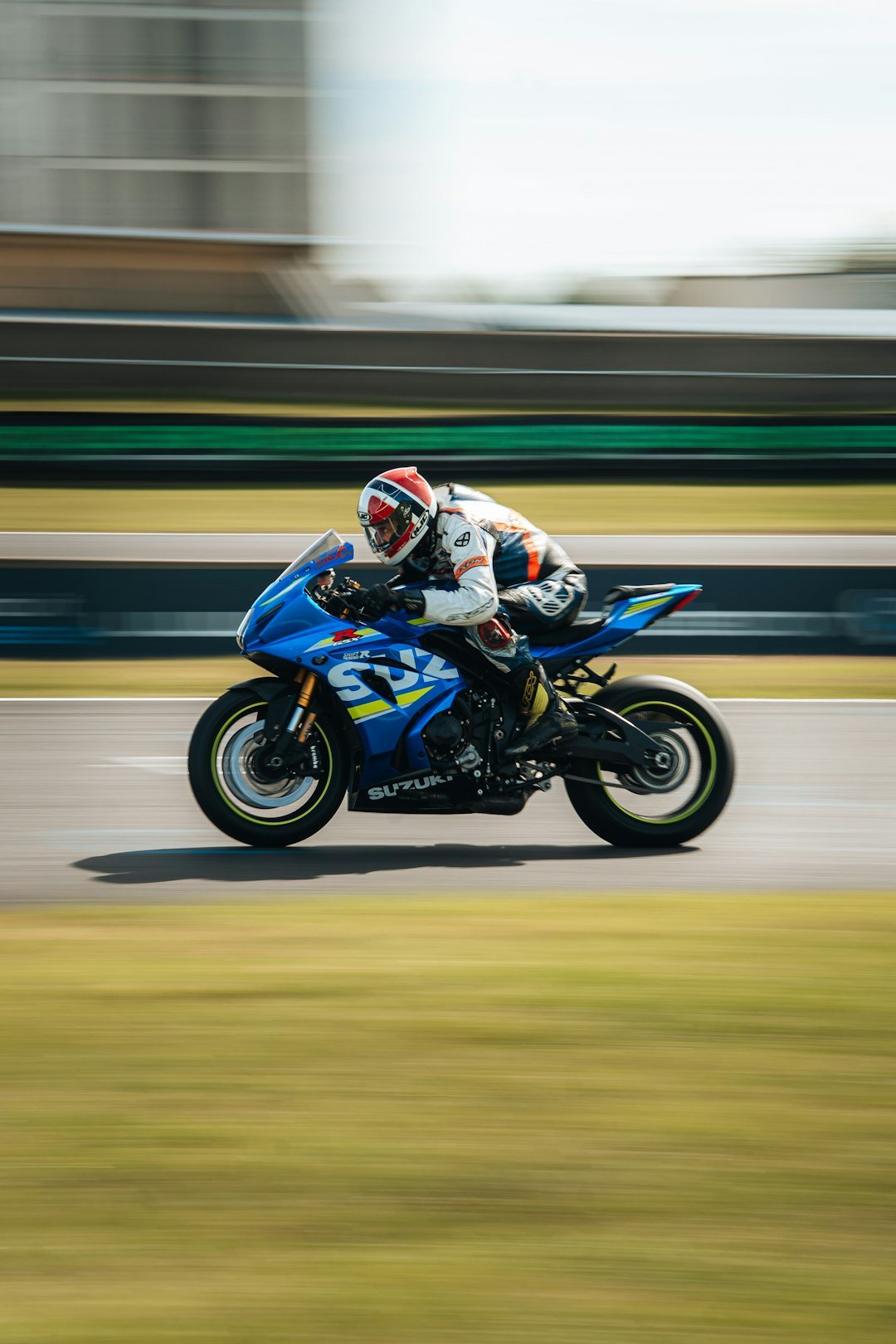 Motorcyclist races a blue suzuki on a track