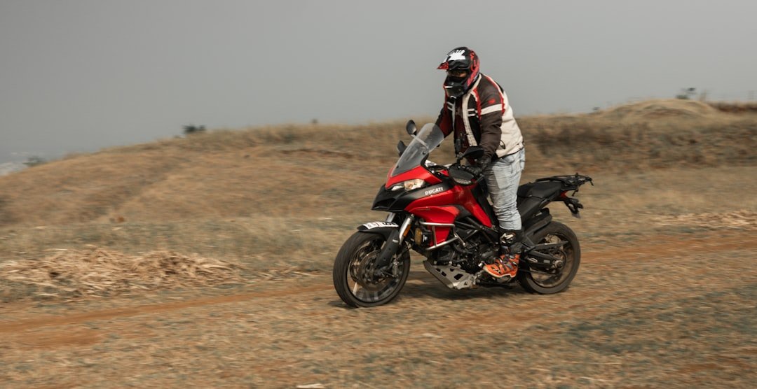 a man riding a red motorcycle down a dirt road