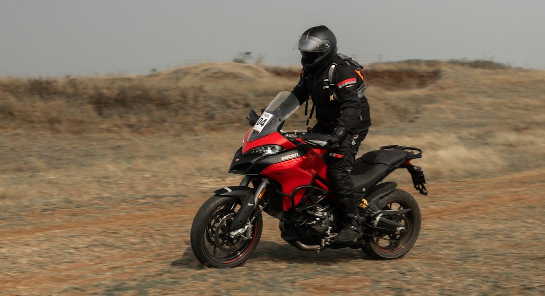 a person riding a red motorcycle on a dirt road