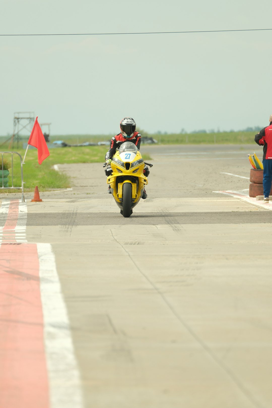 Motorcyclist races on a track with a red flag.
