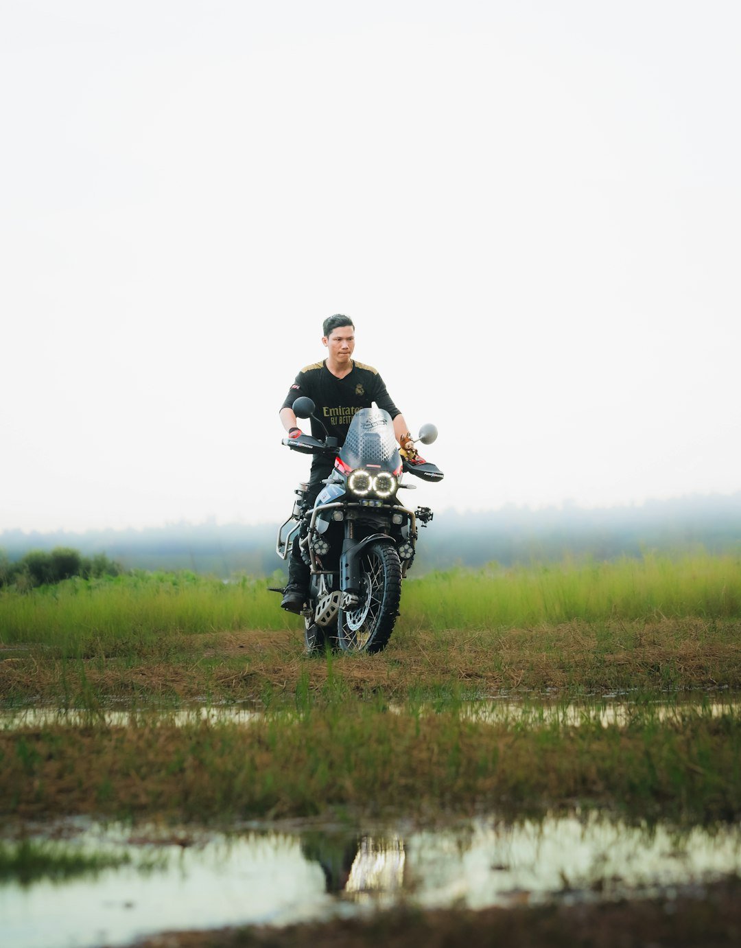 Man riding a motorcycle through a grassy field.