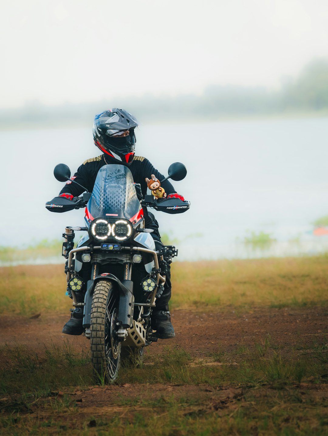 Motorcyclist wearing helmet rides adventure motorcycle by lake
