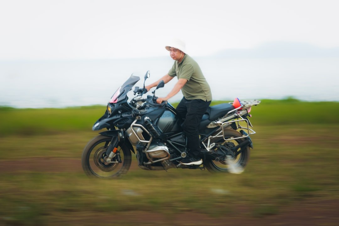 Man riding a motorcycle through a grassy field.