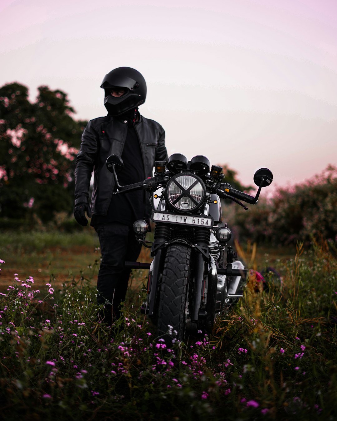 a man standing next to a motorcycle in a field
