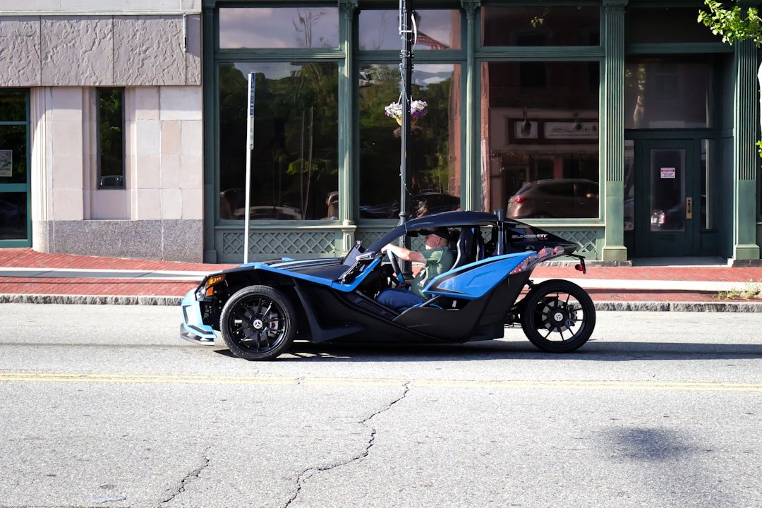 a blue car driving down a street next to a tall building