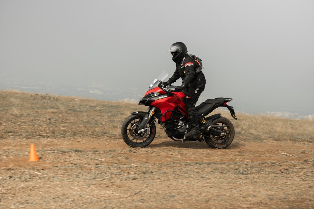 a man riding a red motorcycle on top of a dirt field