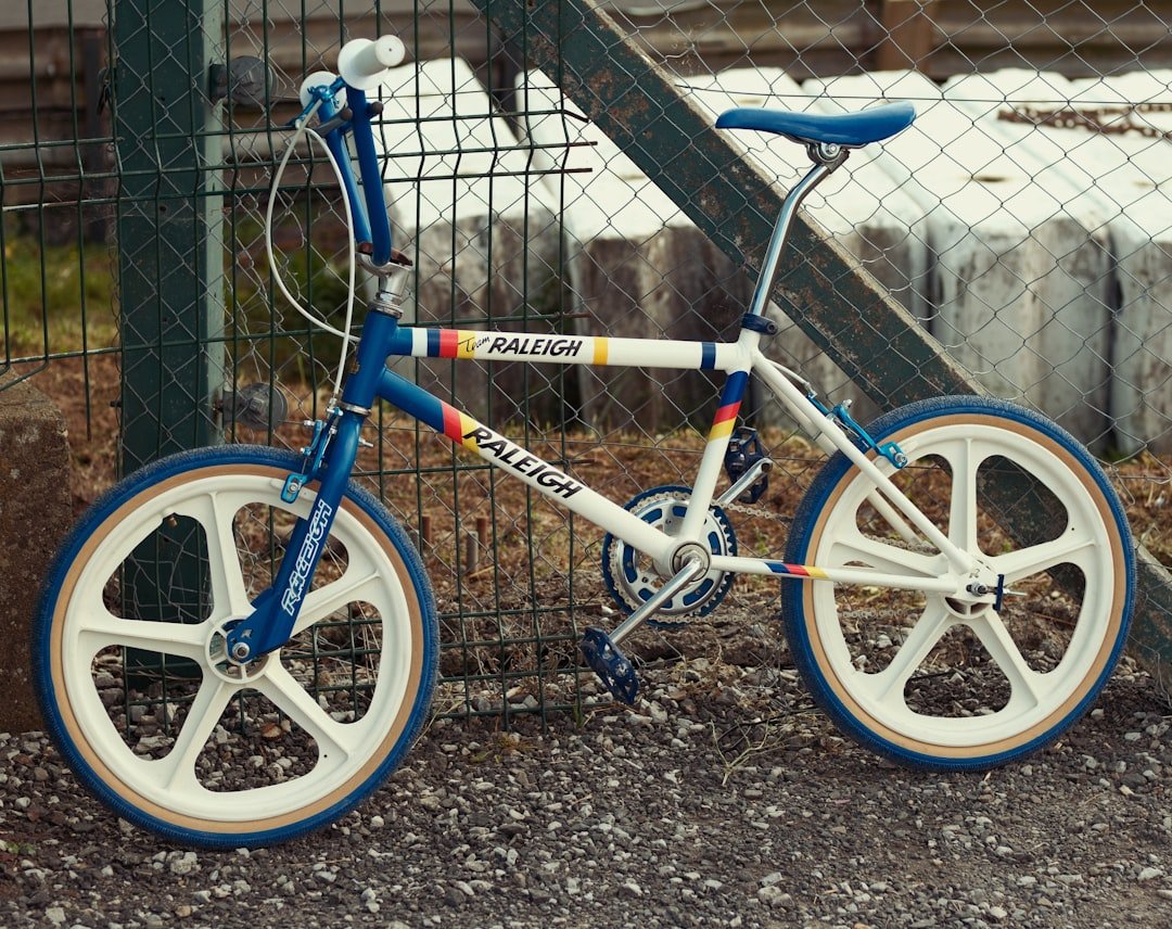 A blue and white bicycle parked in front of a fence