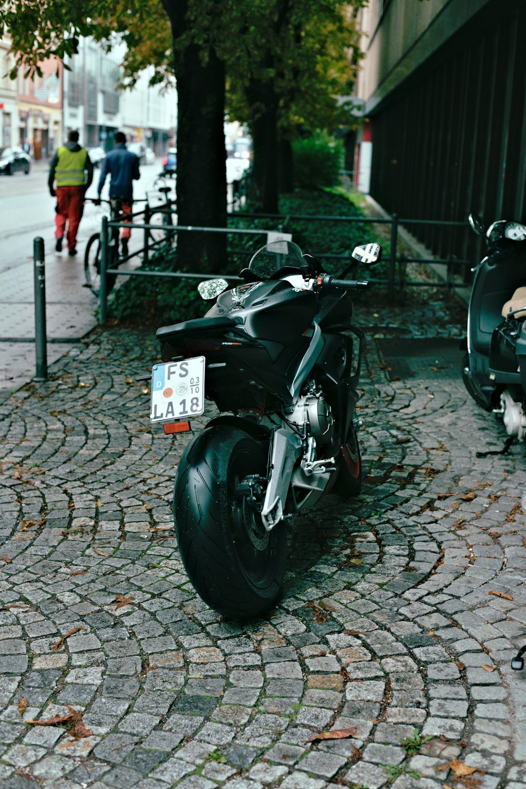 Black motorcycle parked on a cobblestone street.
