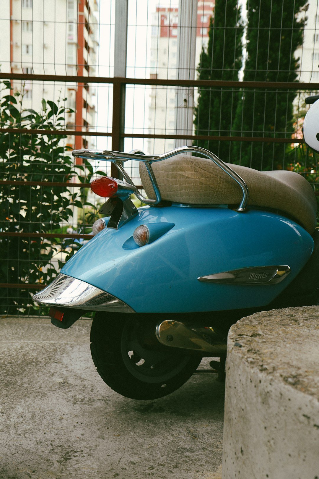 A blue scooter parked next to a cement wall