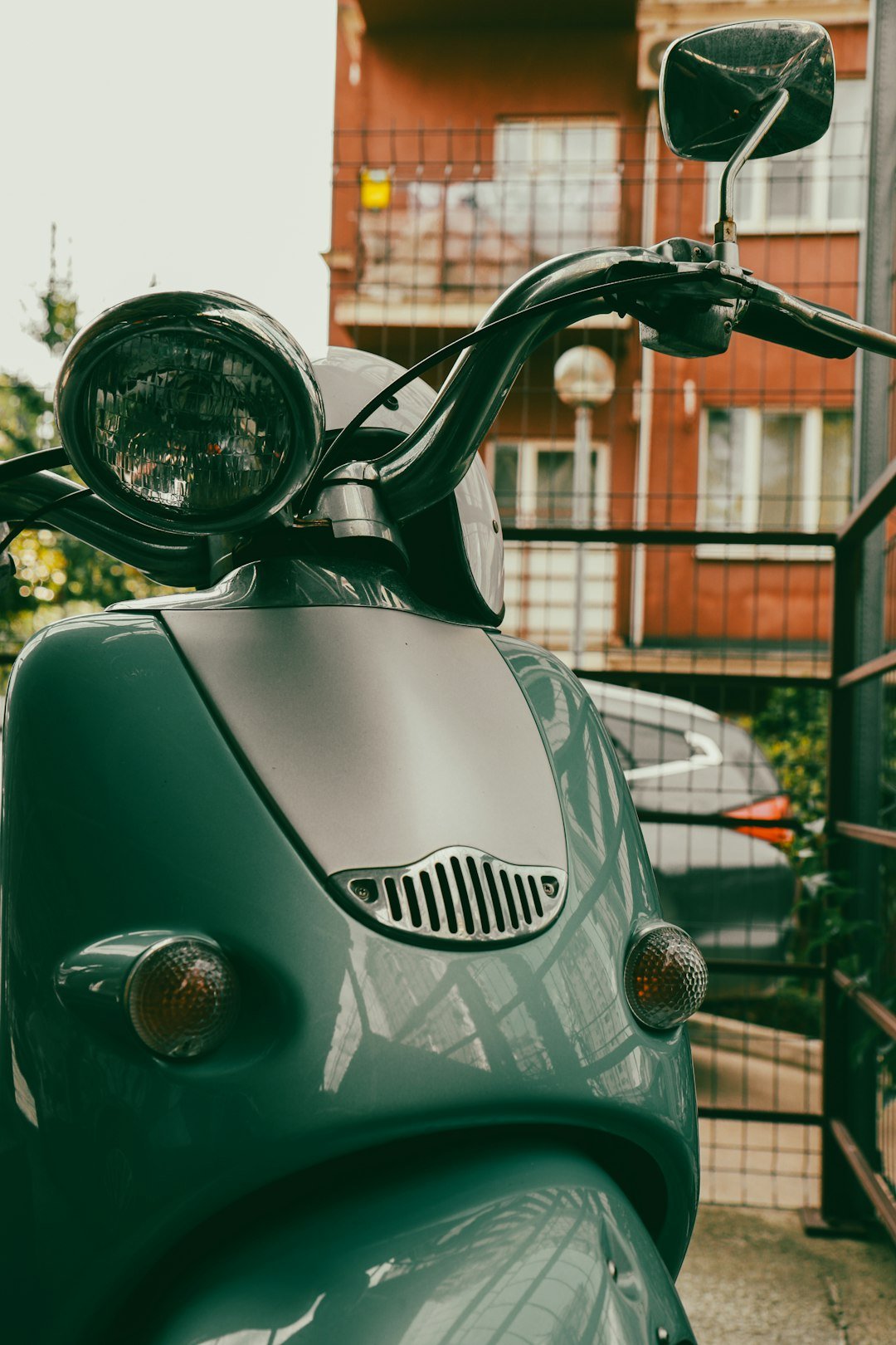 A green scooter parked in front of a building