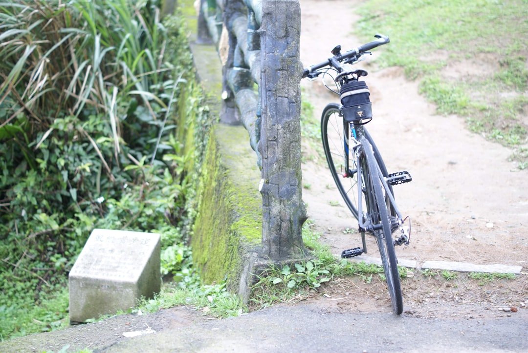 black bicycle parked beside gray concrete wall