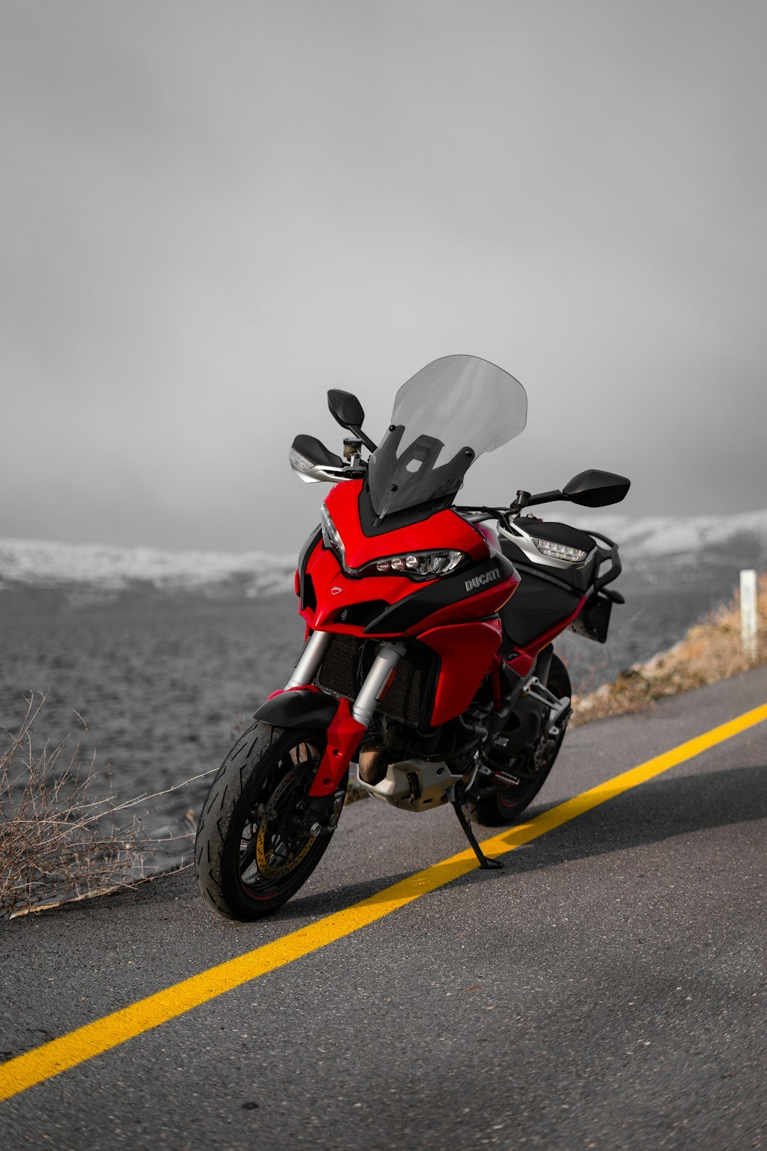 Red motorcycle parked on a road with yellow line
