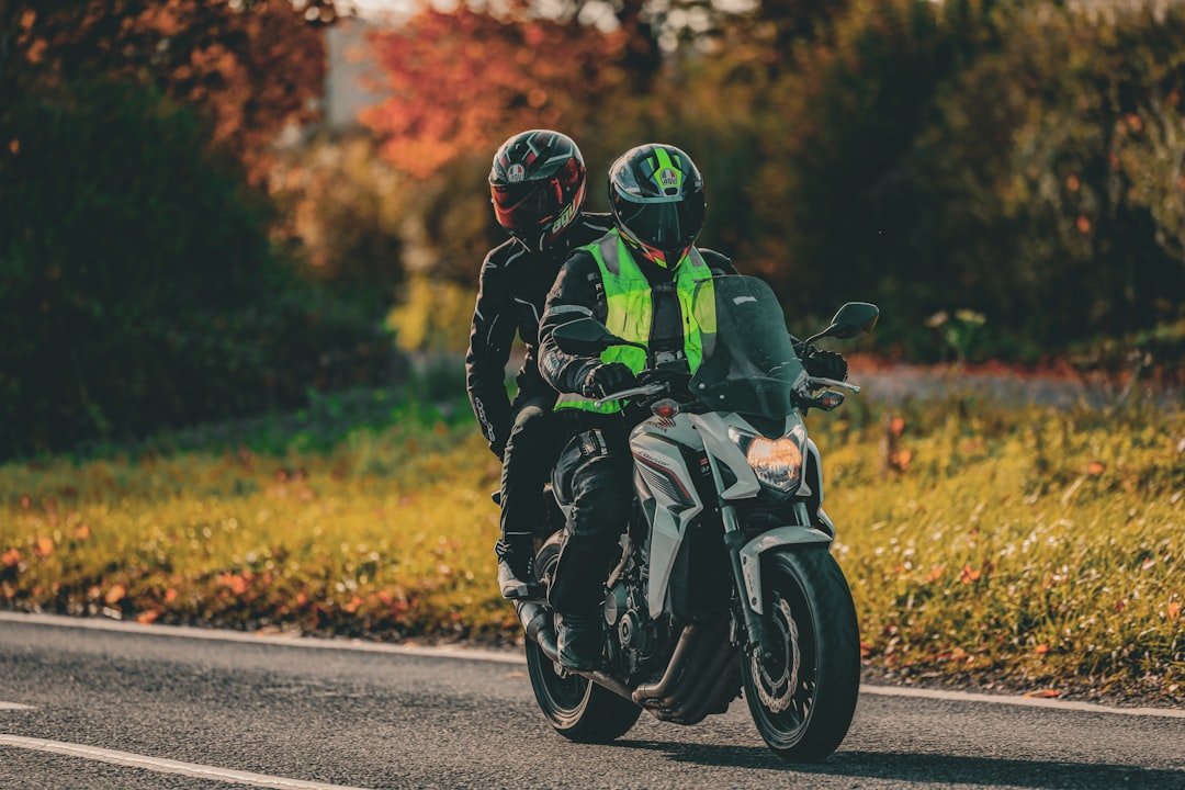 Two people riding a motorcycle on a road