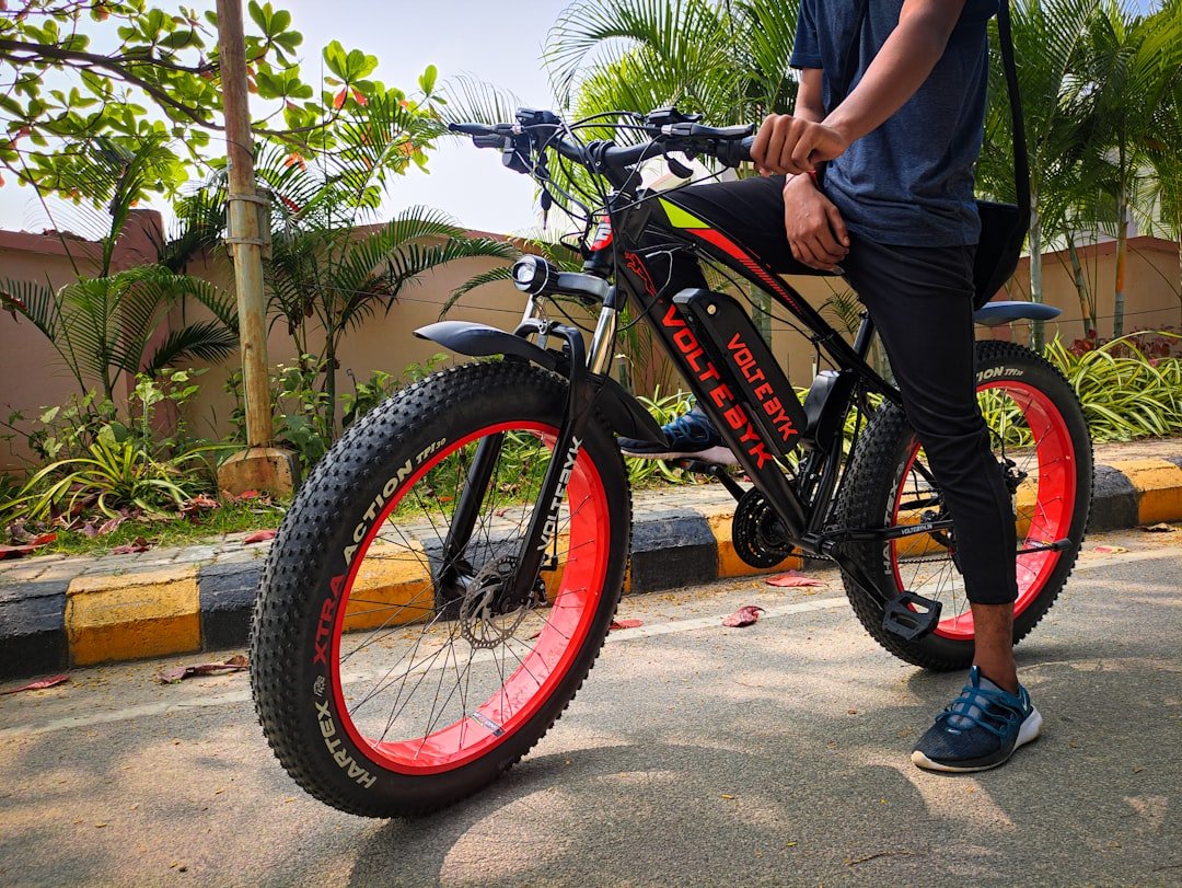 a man standing next to a black and red bike
