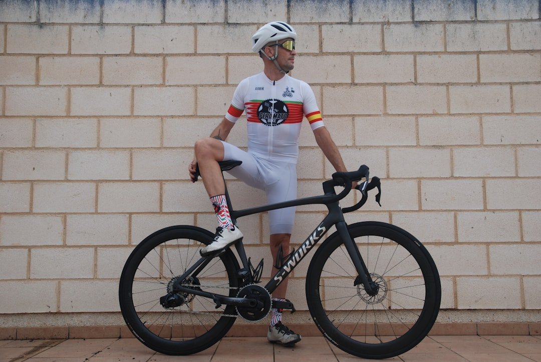 Cyclist in white jersey with bicycle against brick wall