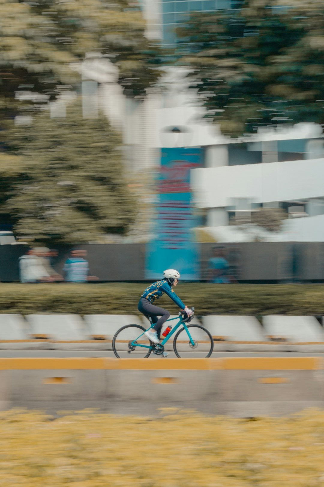 Cyclist rides a bike past a blurred background.