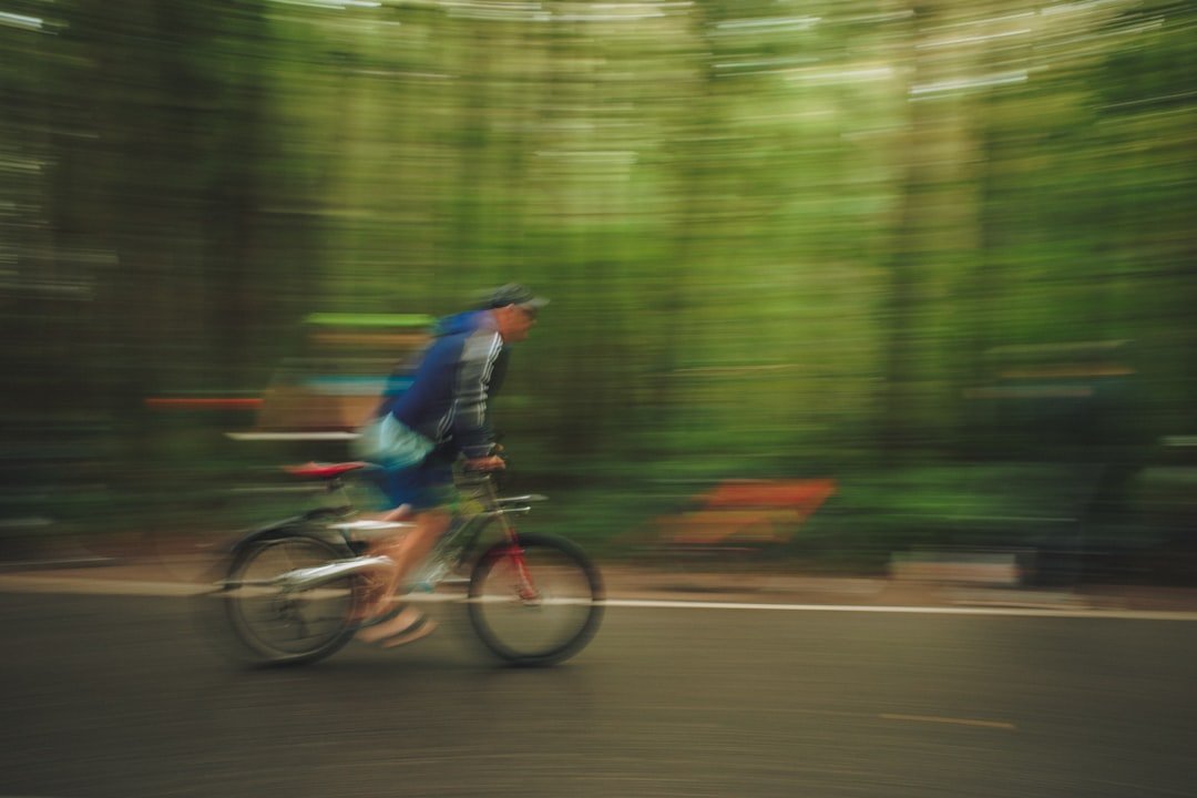 Person cycling on a road with blurred trees