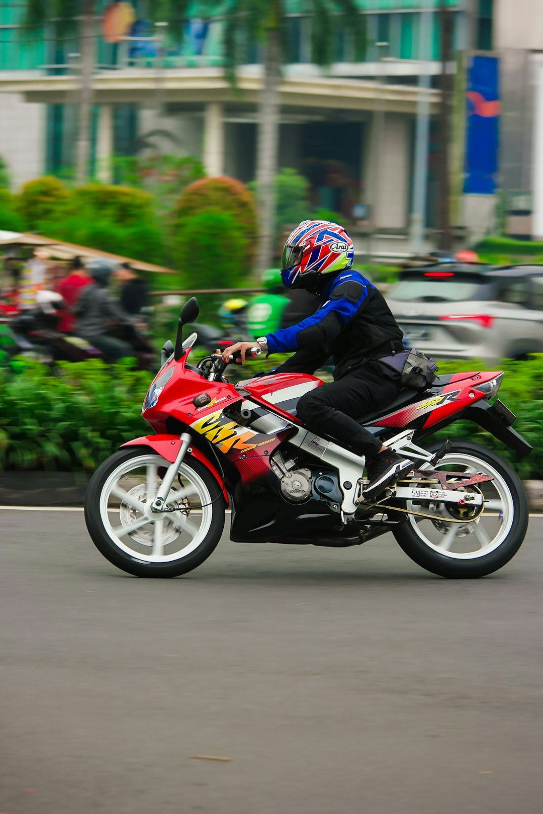 a man riding a red motorcycle down a street