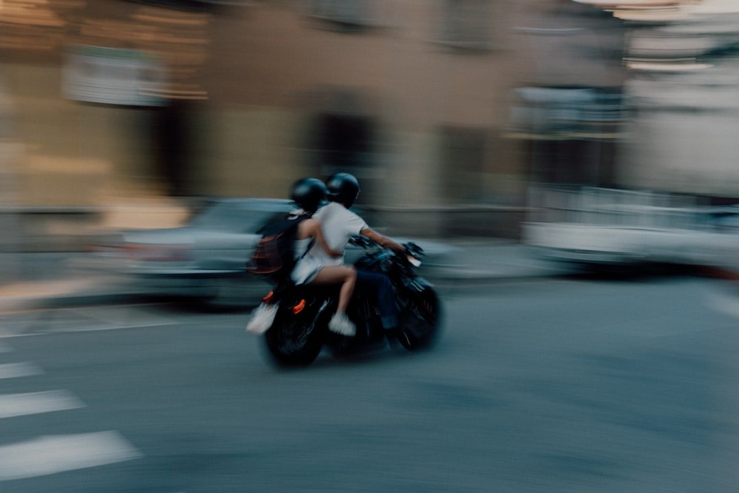 two people riding a motorcycle on a city street